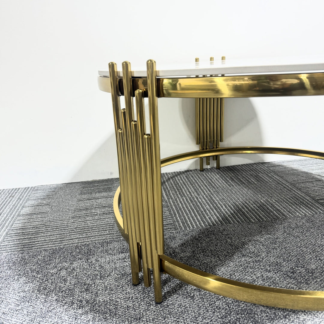 Modern round coffee table with gold metal base and white tabletop on gray carpet