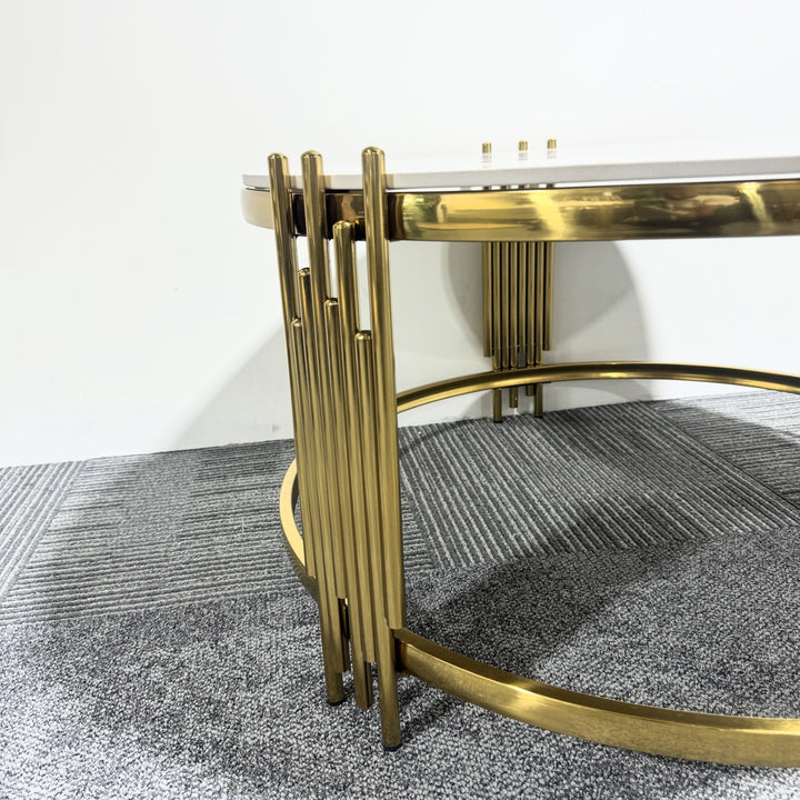 Modern round coffee table with gold metal base and white tabletop on gray carpet