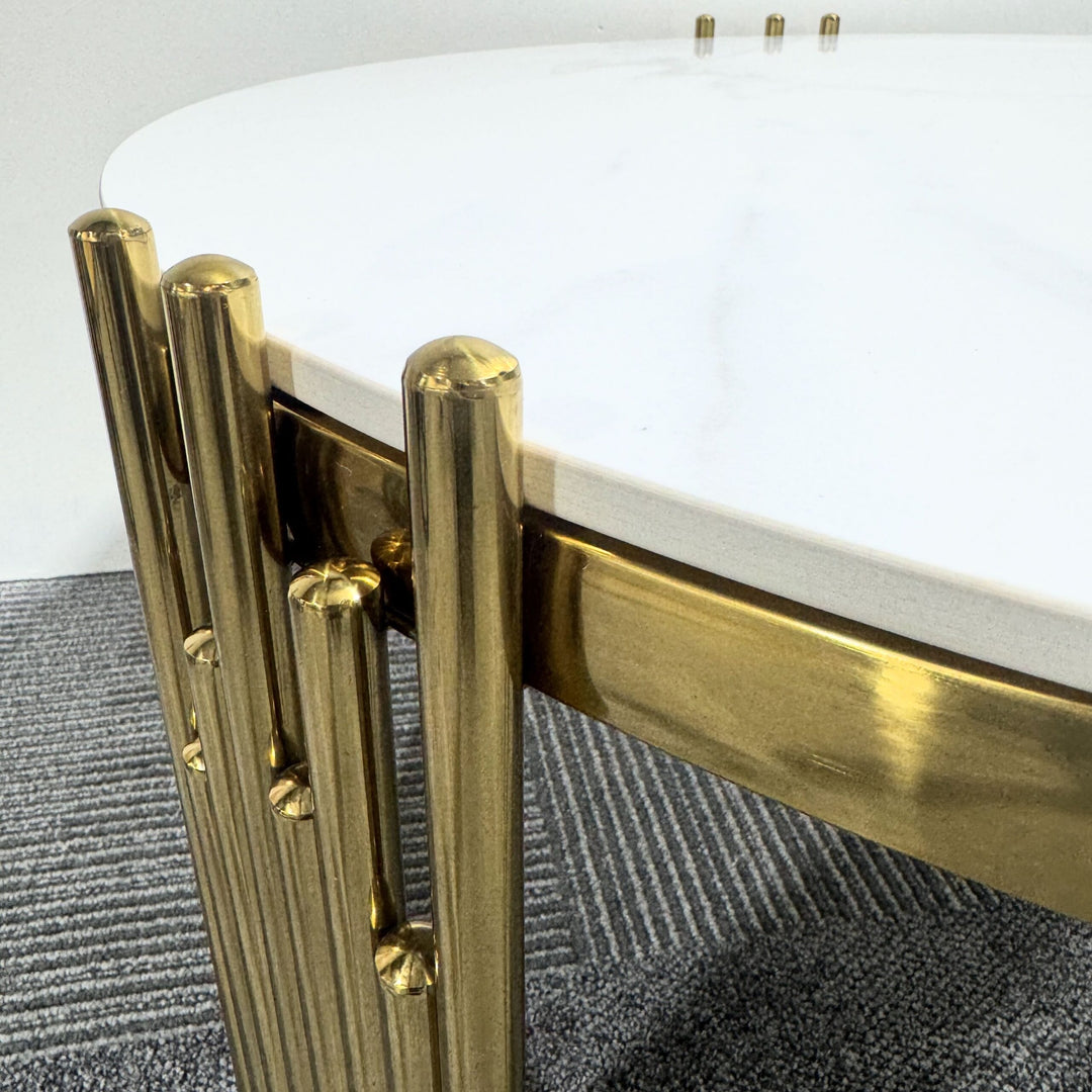 Modern coffee table with white marble top and gold metal legs on gray carpet