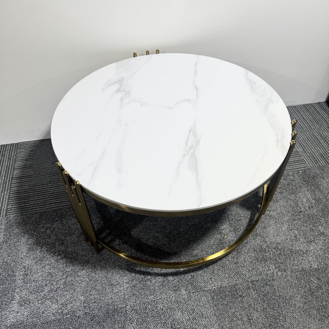 Modern round marble coffee table with gold metal base on grey carpet