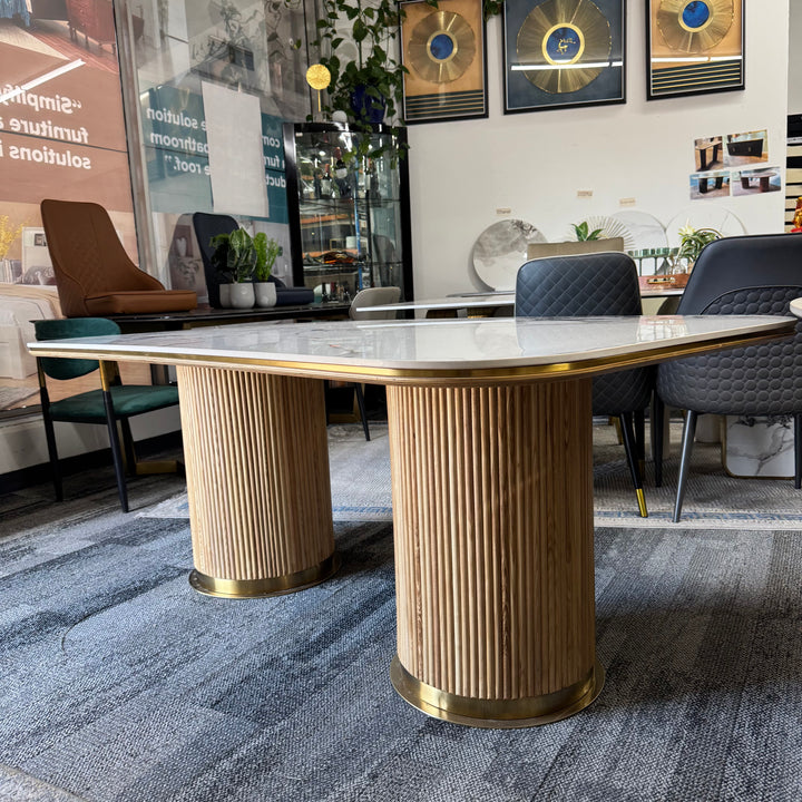 Modern dining table with fluted wood base and marble top in a stylish showroom setting