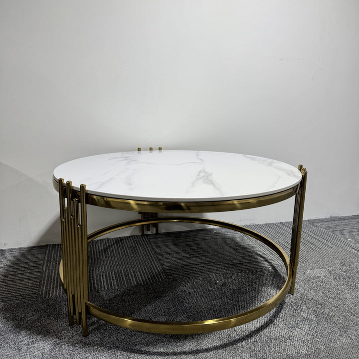 Round coffee table with white marble top and gold metal frame on grey carpet