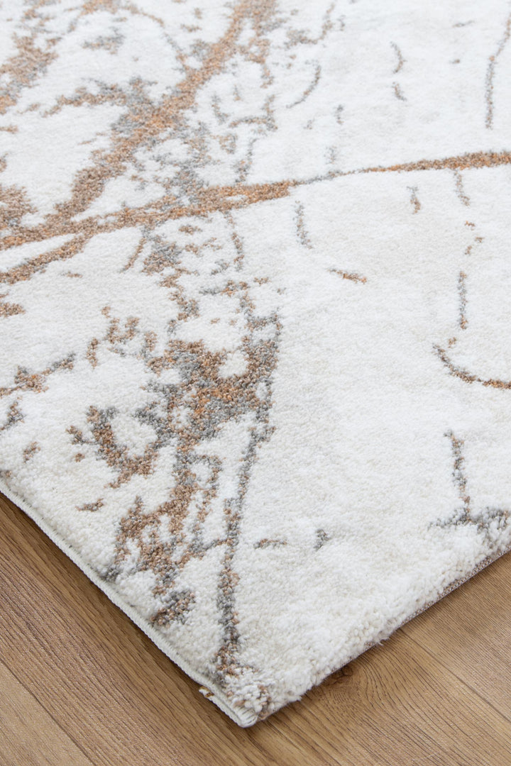 Modern area rug with abstract beige and gray pattern on wood flooring