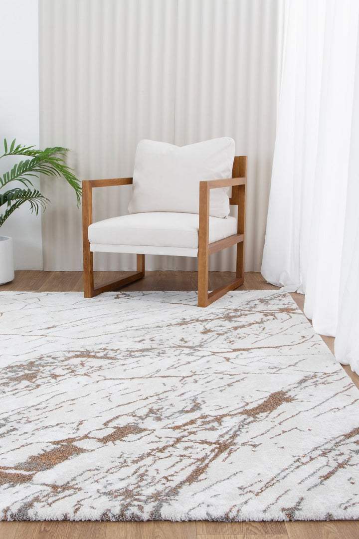 Modern wooden armchair with white cushions on marble-patterned area rug in bright room