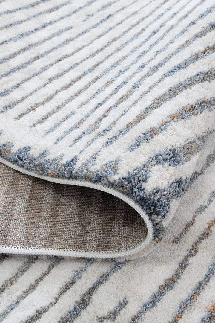 Close-up of a modern area rug with blue, grey, and beige striped pattern