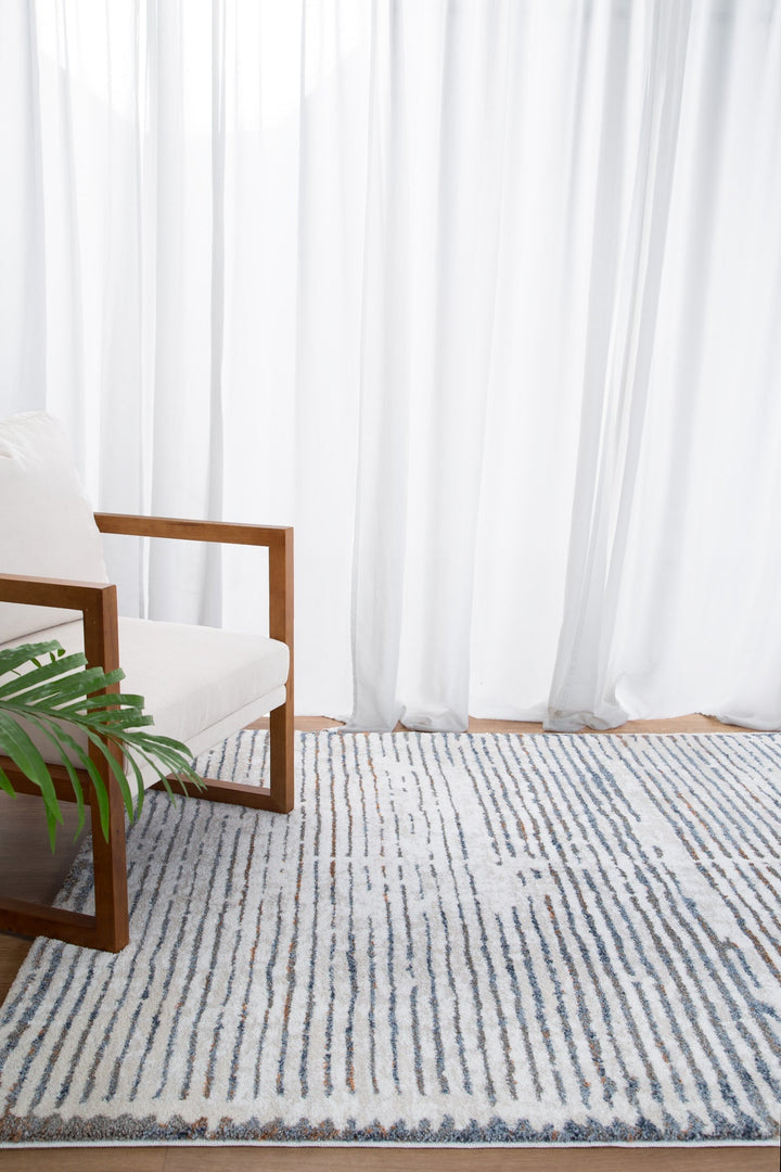 Modern wooden armchair with white cushion on blue and white area rug in bright living room