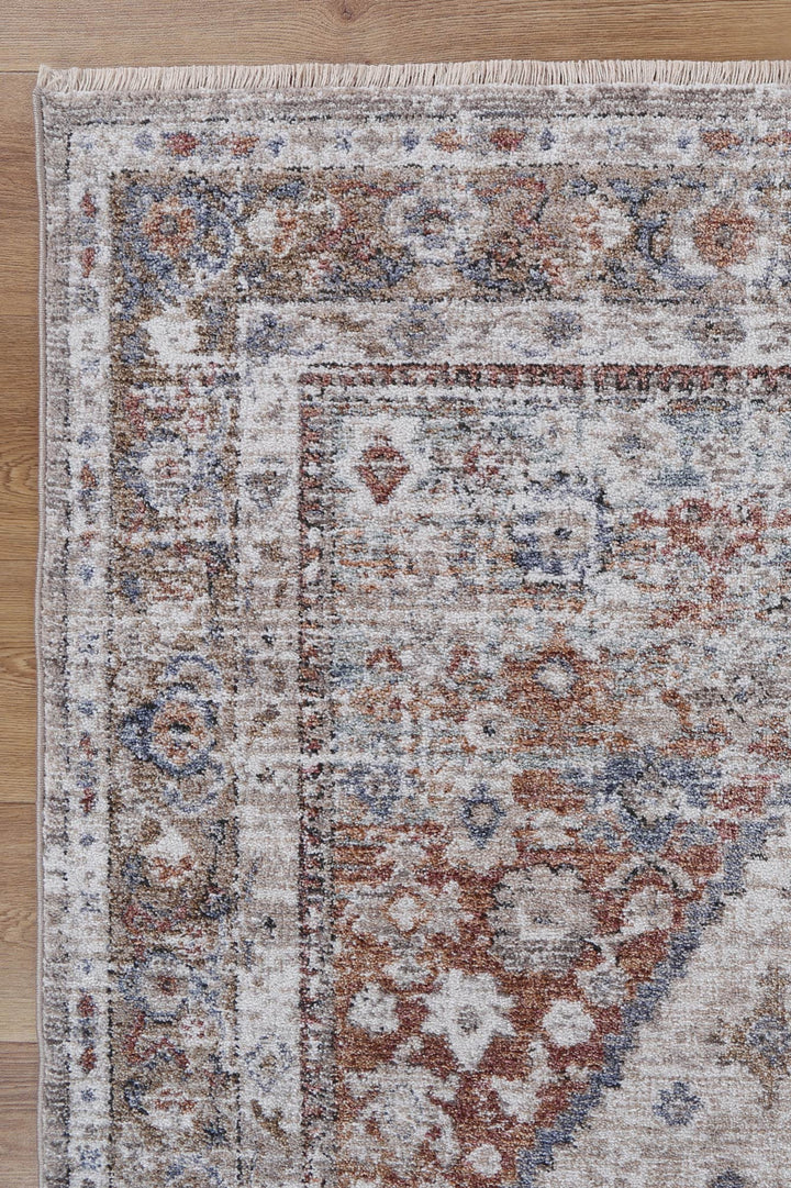 corner of a distressed vintage area rug with ornate pattern on wood floor
