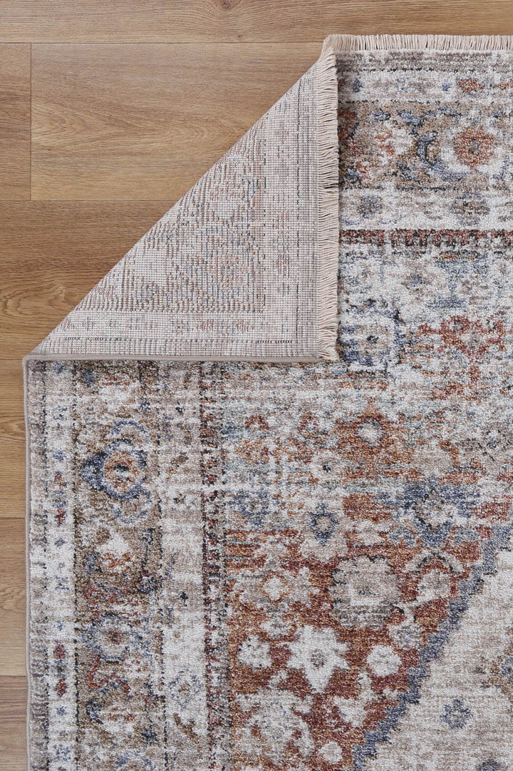 Vintage style area rug with distressed pattern in beige, blue, and rust on wood floor
