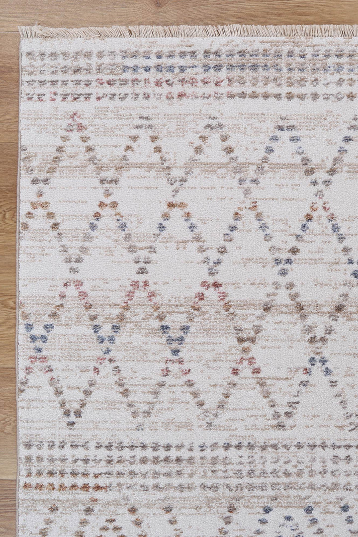Beige patterned area rug with geometric diamond design and fringe on wooden floor