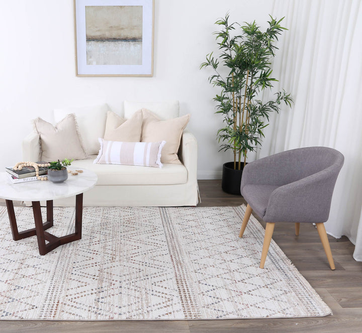 Modern living room with white sofa, decorative pillows, grey accent chair, and patterned rug