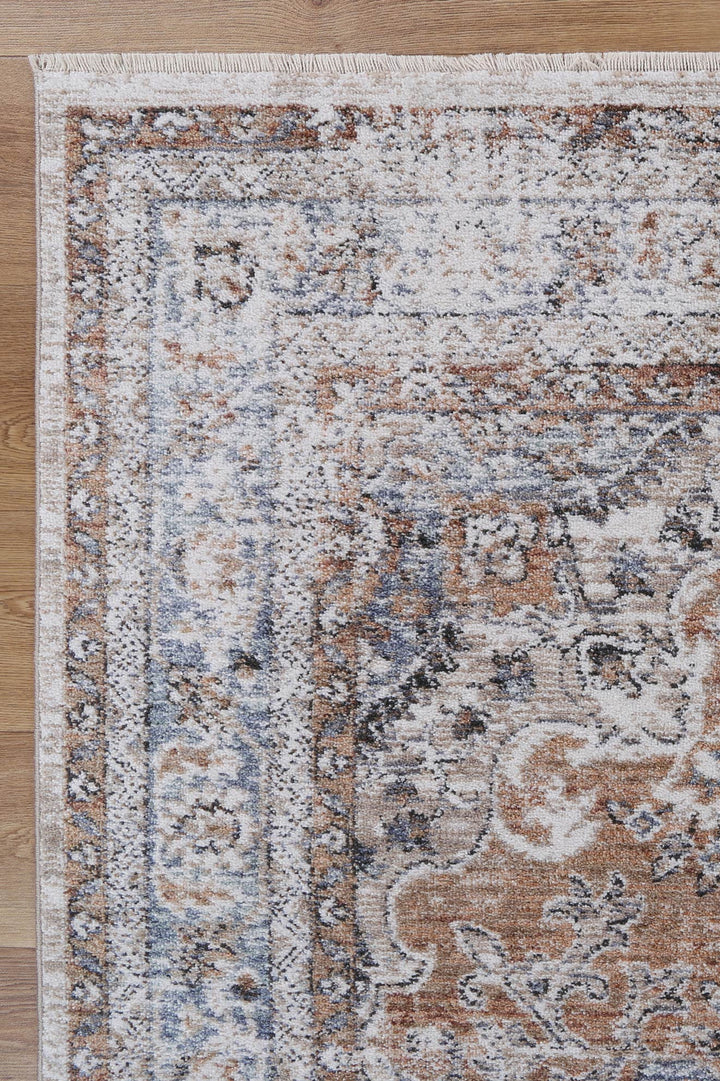 Close-up of a vintage patterned area rug with beige, blue, and brown tones on wood floor