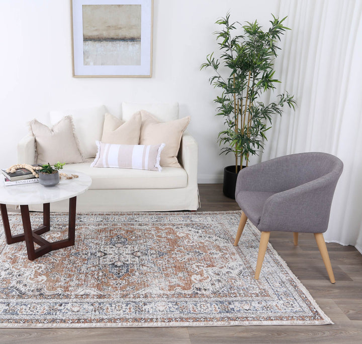 Modern living room with beige sofa, gray accent chair, coffee table, and patterned area rug