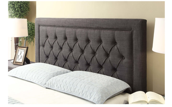 Gray upholstered tufted headboard with pillows, bedside lamps, and home decor