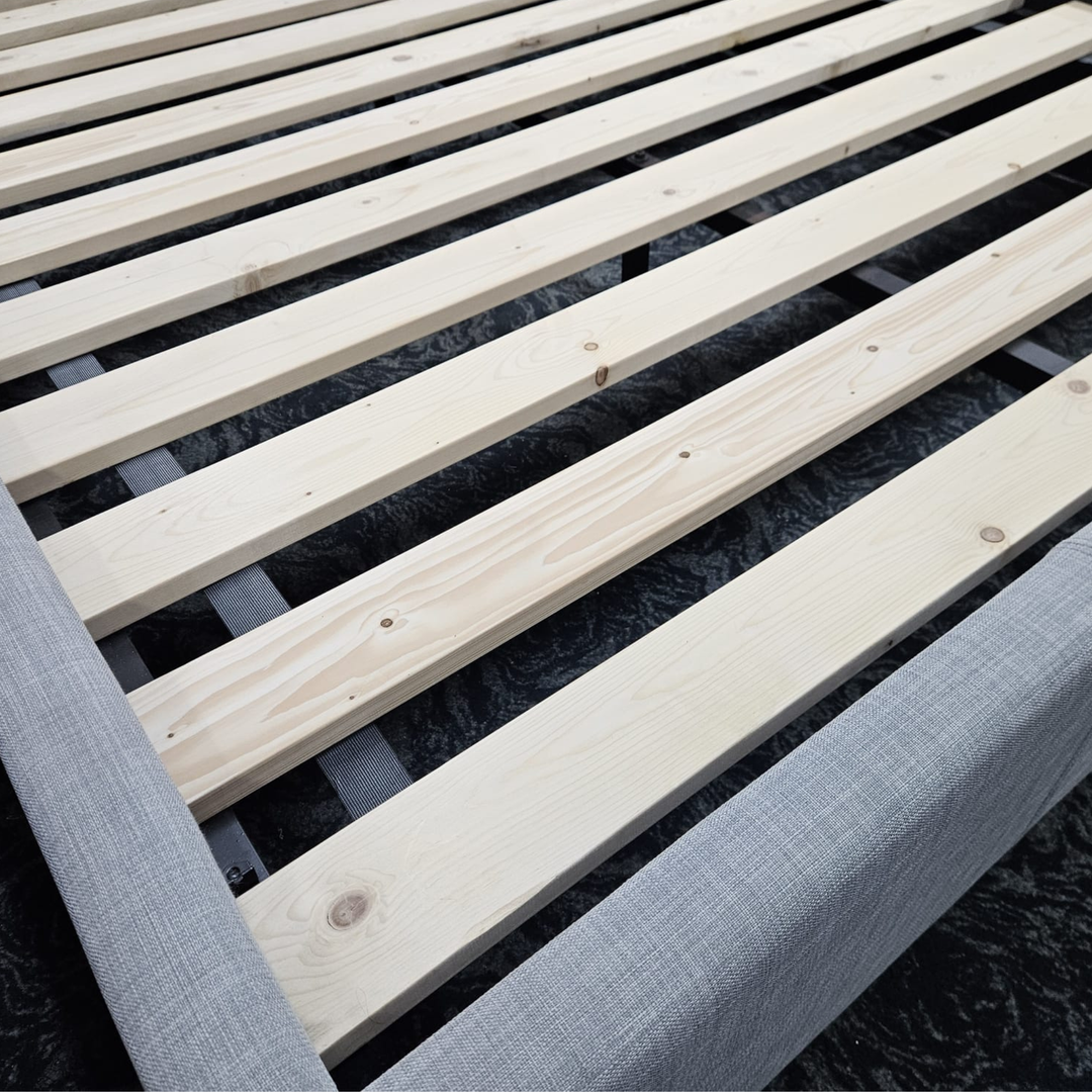 Wooden slatted bed frame with light fabric upholstery, close-up view