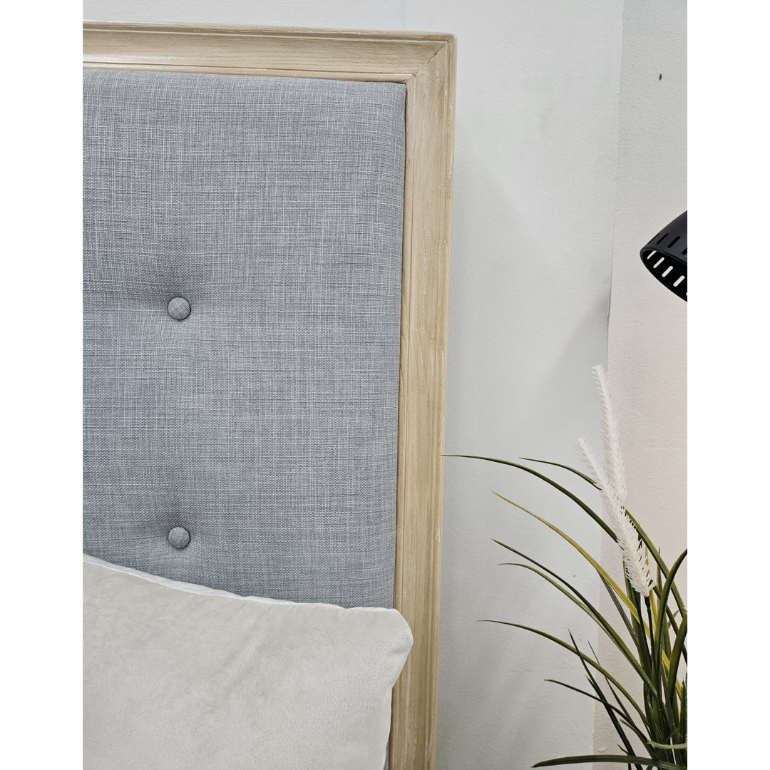 Upholstered grey fabric headboard with wooden frame, modern pillow, and decorative plant