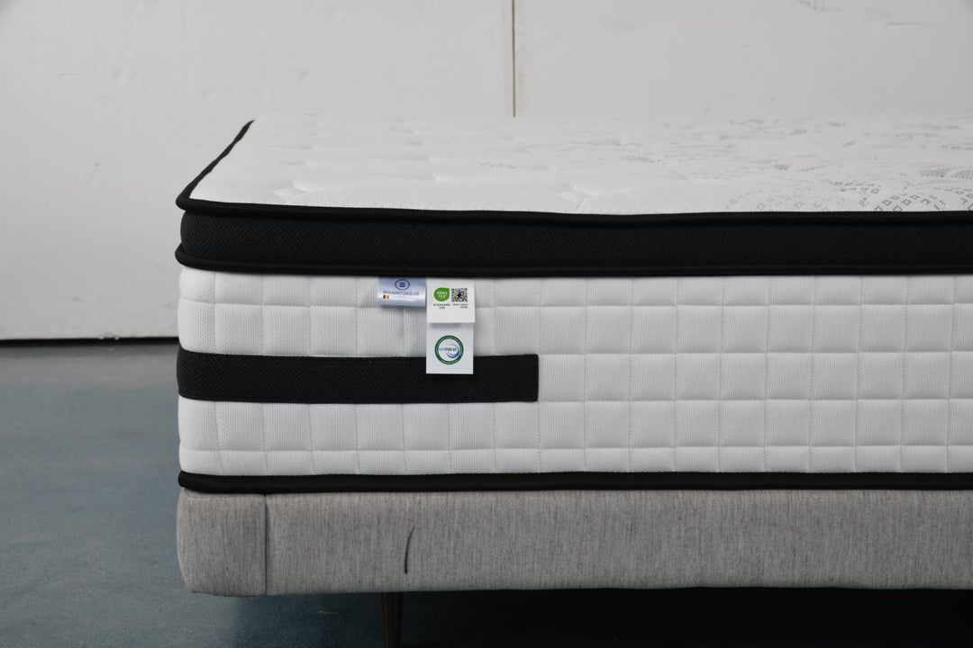 Close-up of a modern hybrid mattress with quilted white and black cover on a bed base