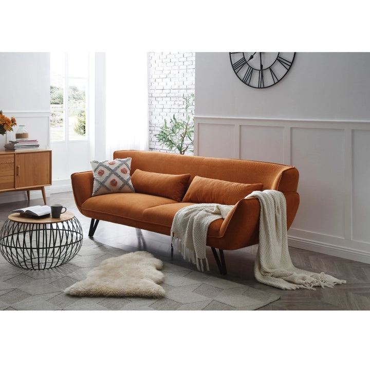 Orange velvet sofa with throw pillows and blanket in modern living room, cozy furniture setup