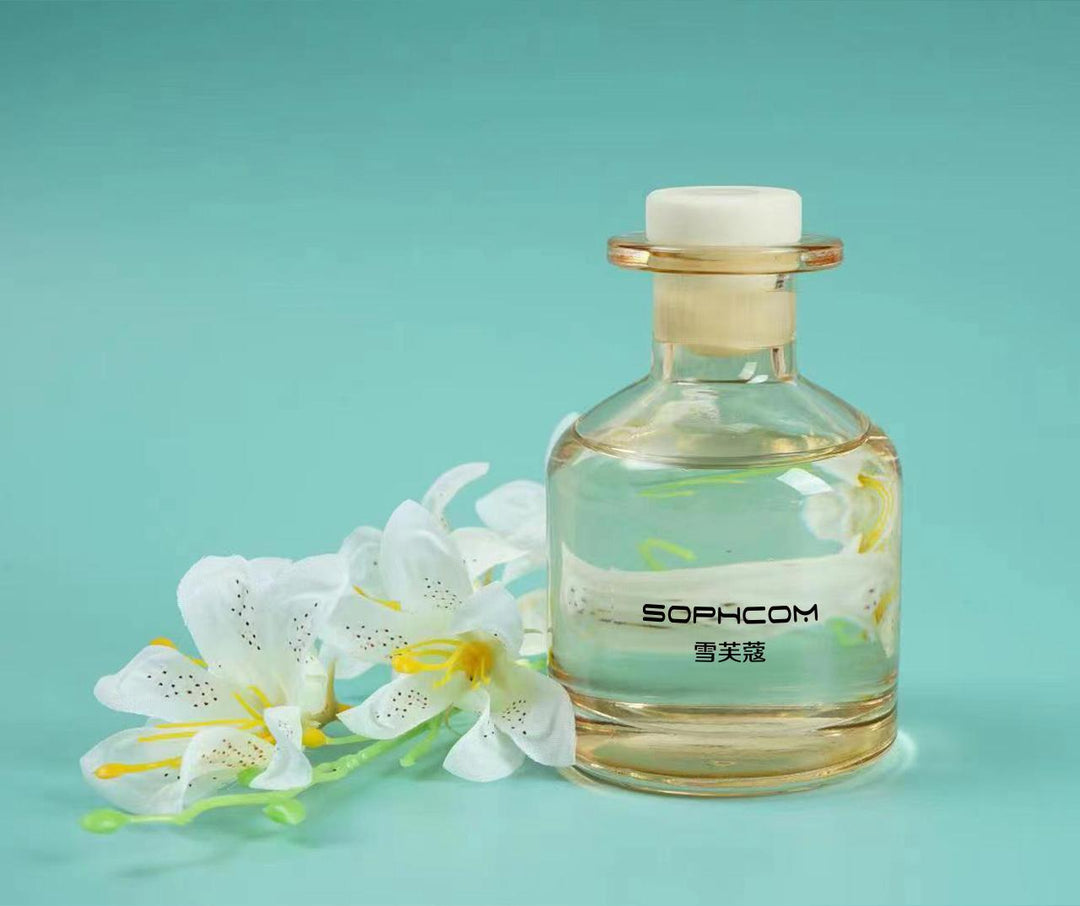 Glass perfume bottle with clear liquid and white lilies on a turquoise background