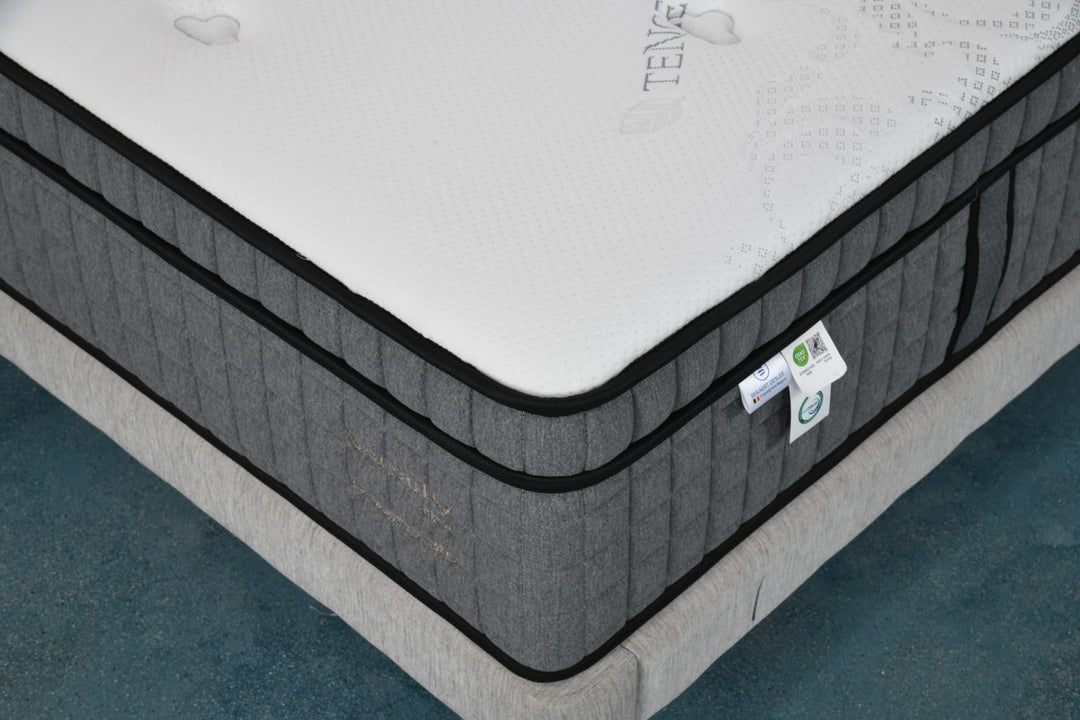 Close-up of a modern gray mattress with quilted sides and white top, on a bed base