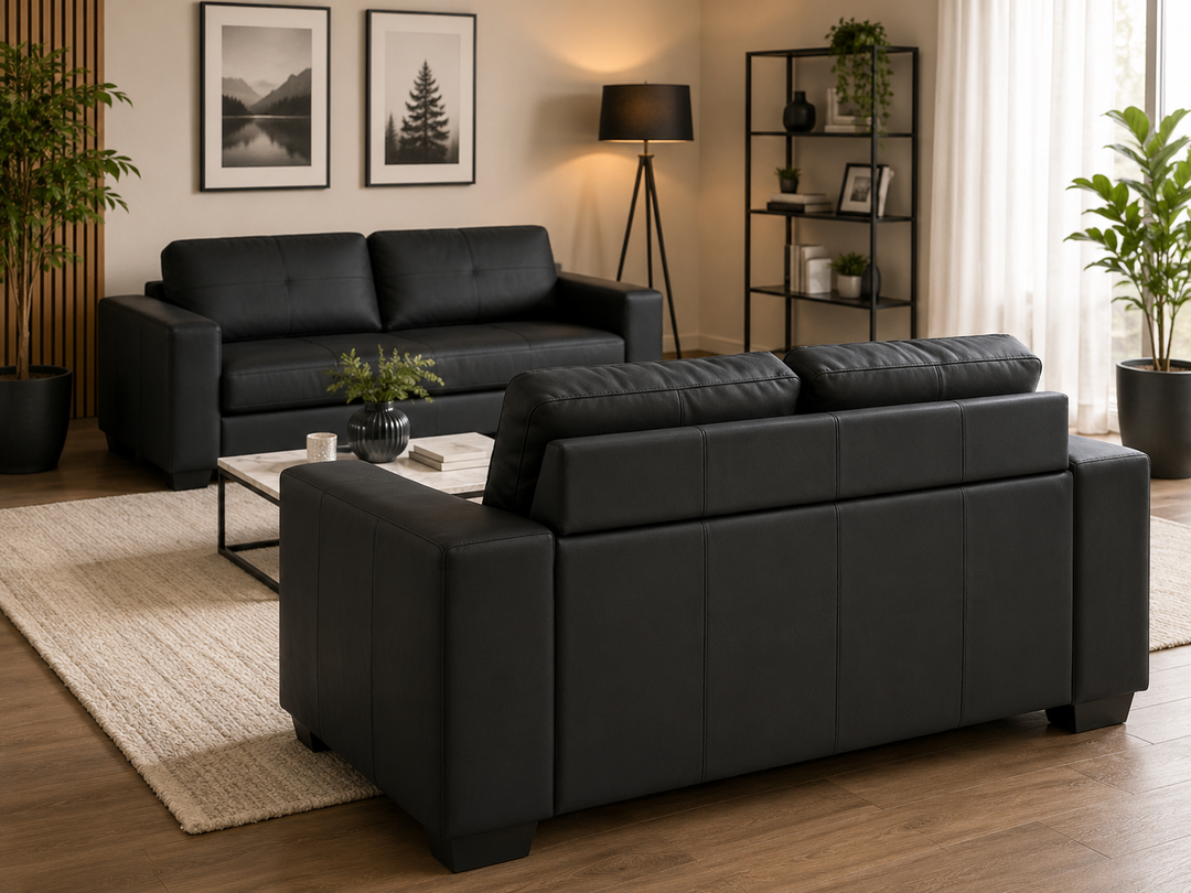 Black leather sofa set in modern living room with rug, plants, and wall art