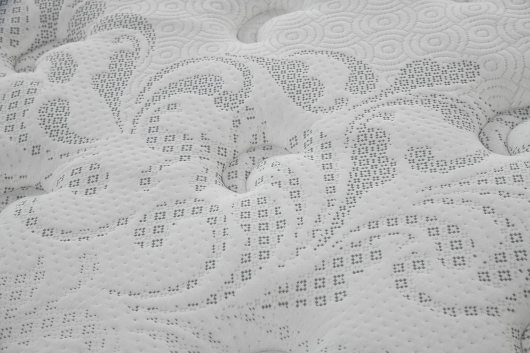 Close-up of white mattress surface with quilted floral pattern and textured stitching