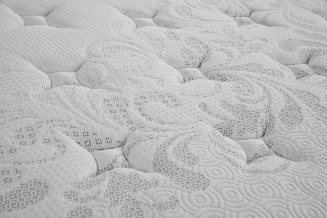 Close-up of a white quilted mattress surface with soft patterned stitching