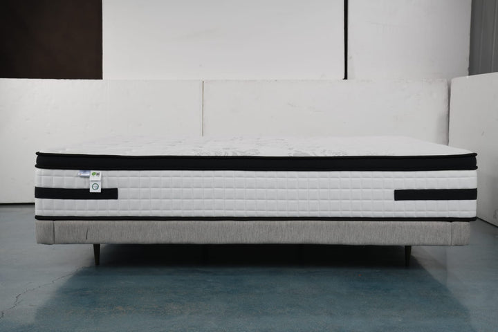 Modern white mattress with black trim on upholstered bed base, home furniture setting