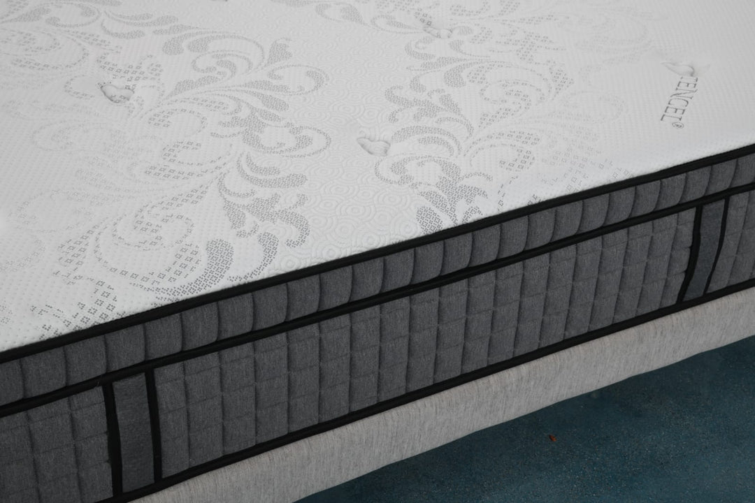 Modern mattress with patterned white top and dark gray quilted sides on a bed frame