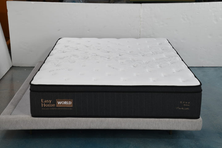 Pillow top mattress with patterned white surface on a light grey upholstered bed frame