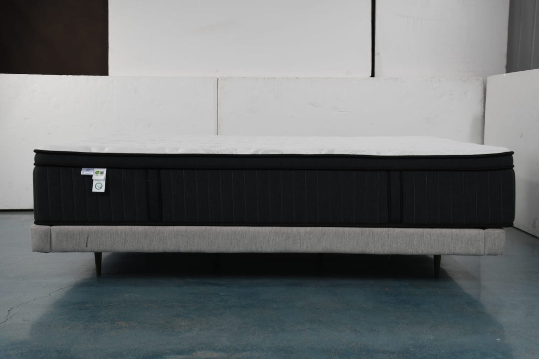 Modern black and white mattress on upholstered bed frame in a minimalist room