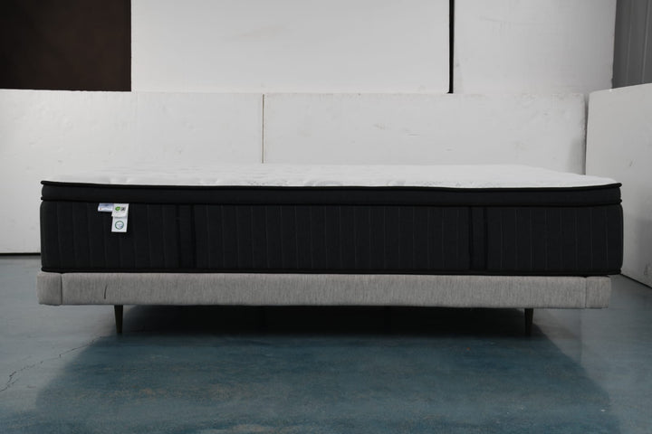 Modern black and white mattress on upholstered bed frame in a minimalist room