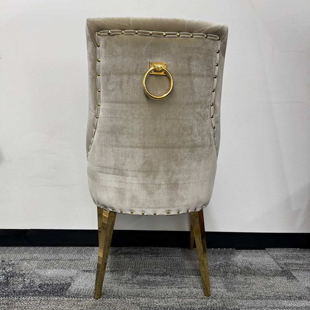 Beige velvet chair with gold metal legs and decorative gold ring on the backrest
